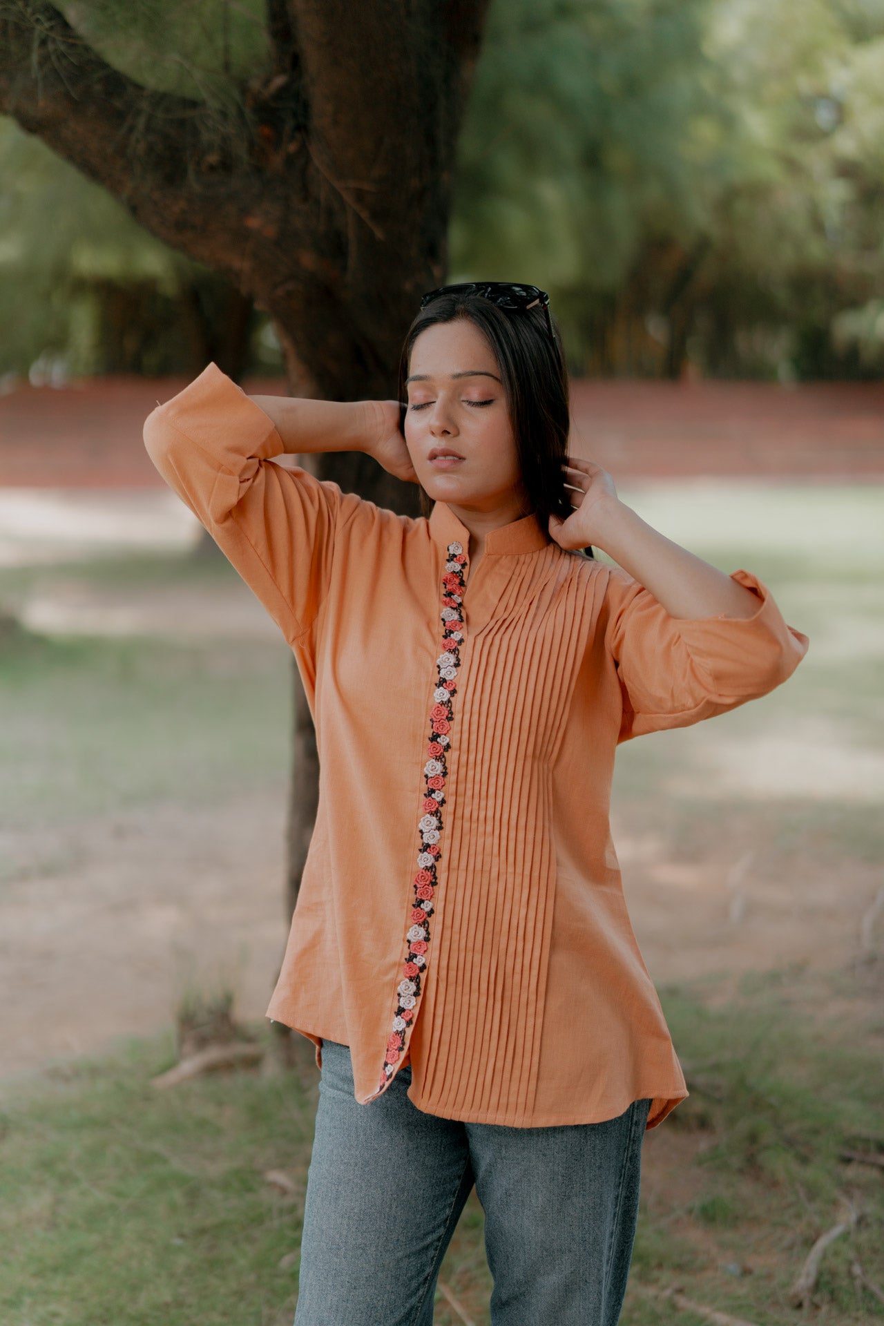 Orange pleated shirt with floral embellishment