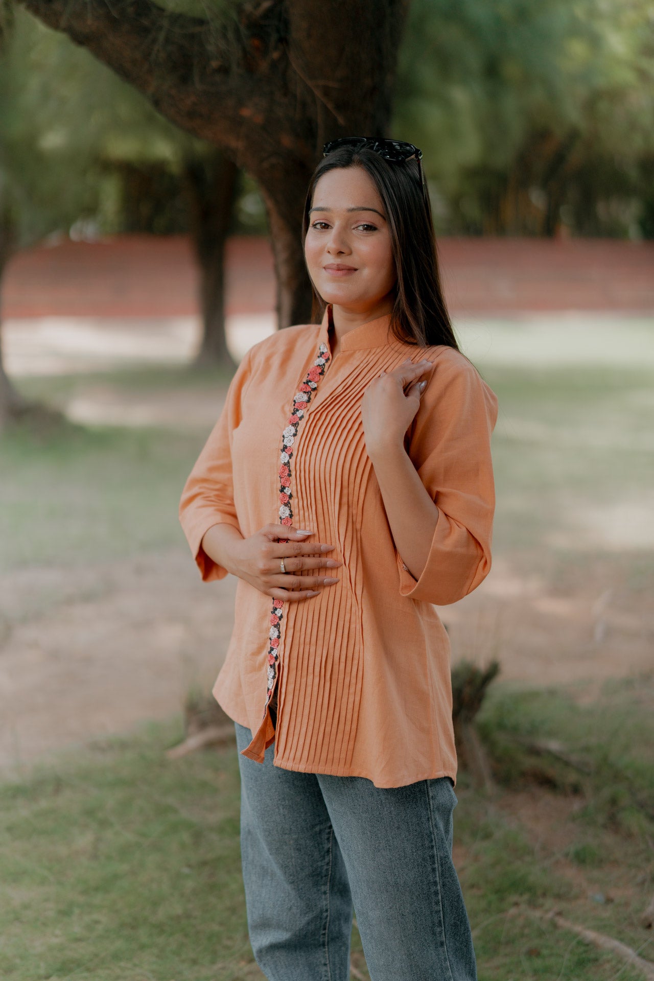 Orange pleated shirt with floral embellishment