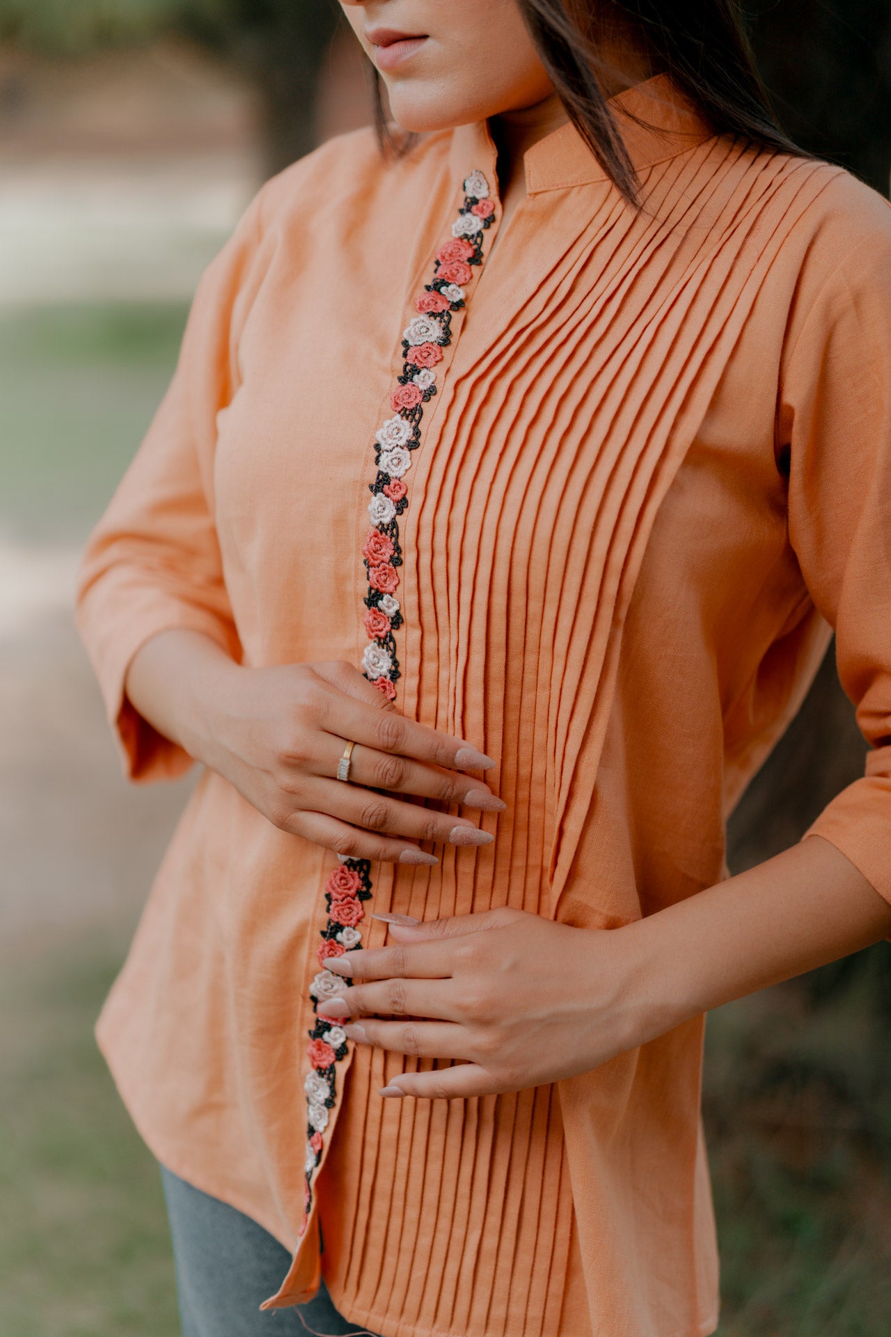 Orange pleated shirt with floral embellishment