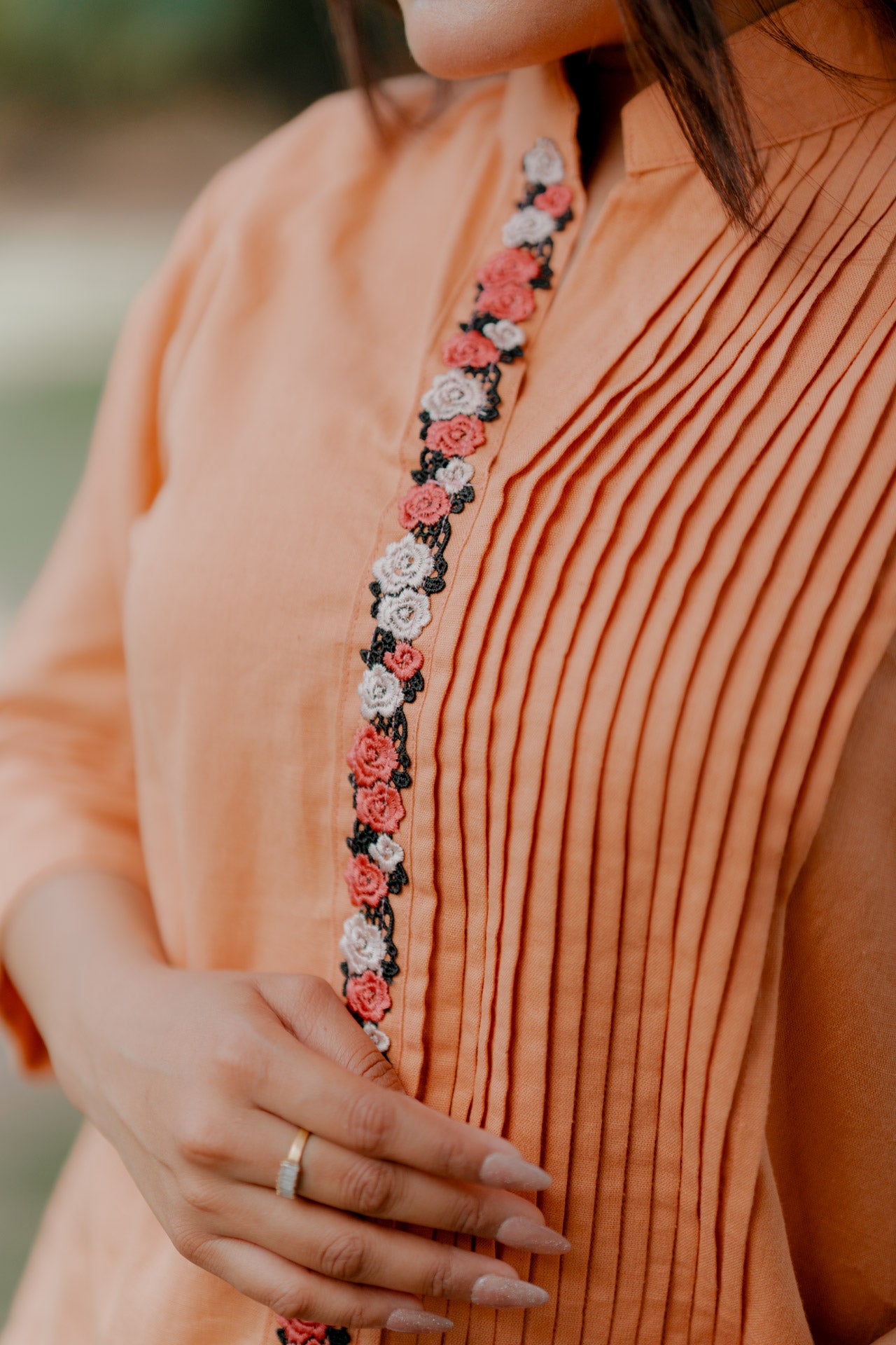 Orange pleated shirt with floral embellishment